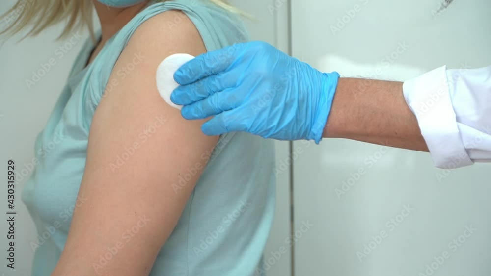 Nurse in gloves vaccinates female patient in mask in clinic. Doctor injects medicine into hand from syringe. Covid-19, coronavirus vaccine Nurse in gloves vaccinates female patient in mask in clinic. Doctor injects medicine into hand from syringe. Covid-19, coronavirus vaccine