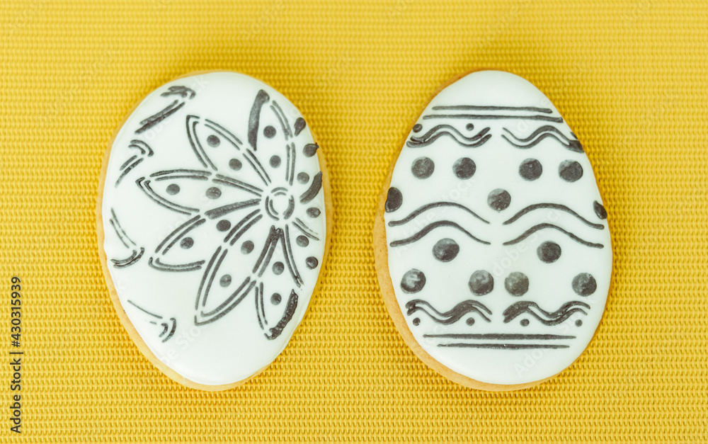 Easter glazed cookies in the form of eggs on a yellow background that can be painted with a brush and food colors Easter glazed cookies in the form of eggs on a yellow background that can be painted with a brush and food colors