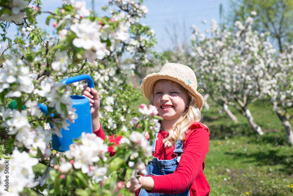 Blonde little girl playing in a blossoming orchard