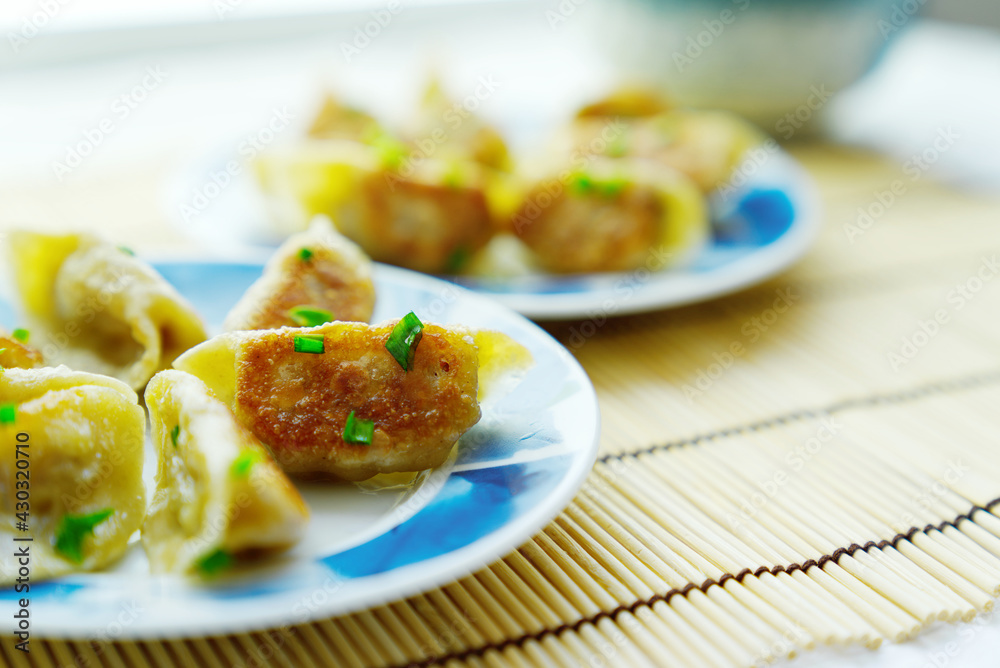 Close-up of golden fried buns with chopped green onion in a blue lace plate, depth of field effect