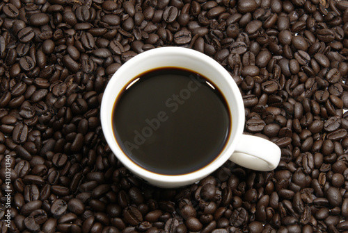 A cup of coffee, coffee beans background, top view