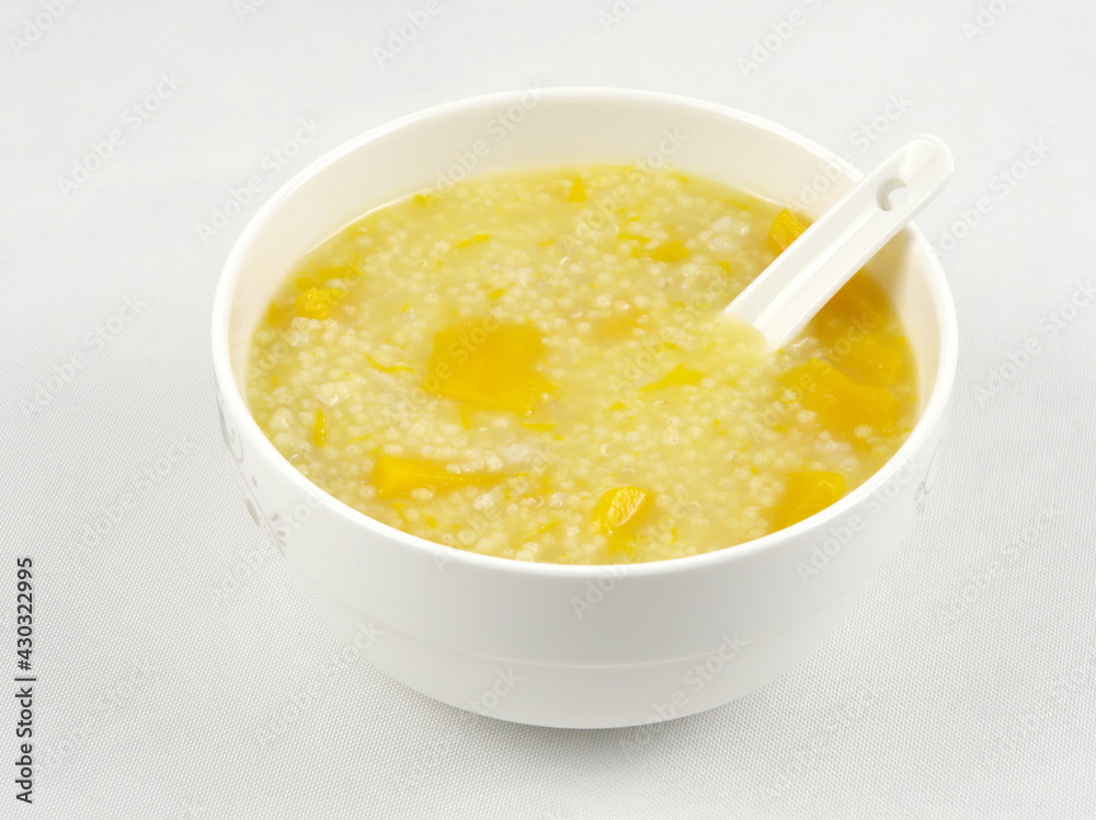 A bowl of nutritious and delicious pumpkin millet porridge with a spoon in it, white background A bowl of nutritious and delicious pumpkin millet porridge with a spoon in it, white background