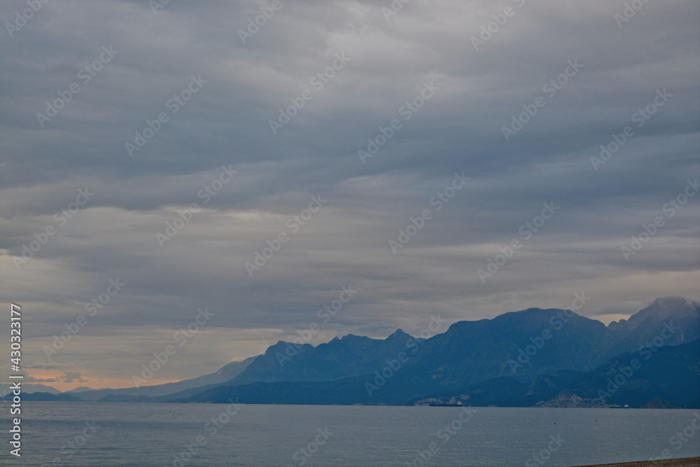 clouds over the mountains with grey sea in cloudy day