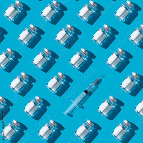 Fototapete Vaccine vials and syringe on a cyan background , flat lay pattern minimalistic c