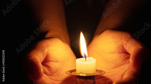 Close-up of a hand holding a small half lit candle on a candlestick