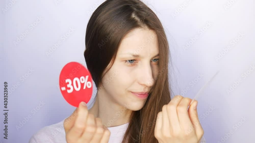 A very beautiful girl holding two red round signs with -30 percent discount and smiling close-up A very beautiful girl holding two red round signs with -30 percent discount and smiling close-up