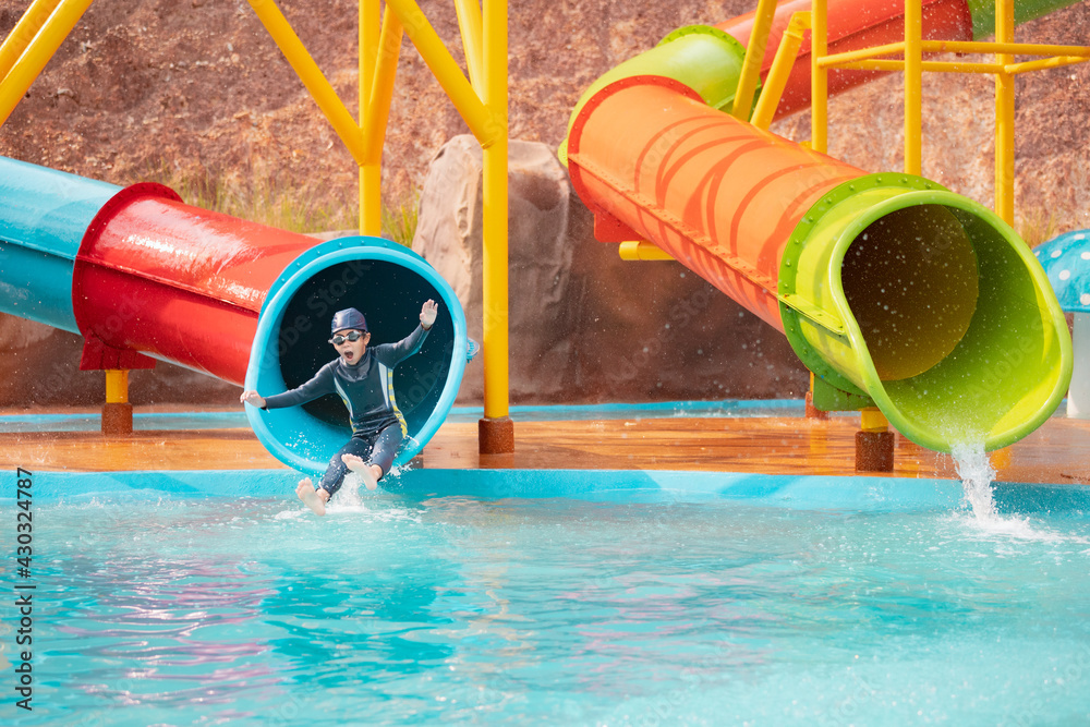 Asian child girl having fun to slide down on water slide in a water ...