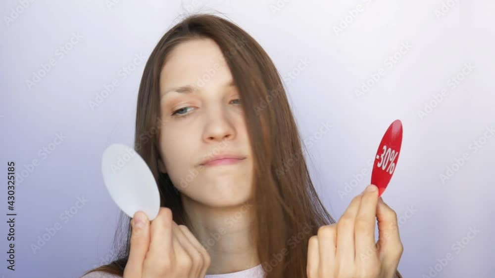 A very beautiful girl holding two red round signs with -30 percent discount and showing them close-up A very beautiful girl holding two red round signs with -30 percent discount and showing them close-up
