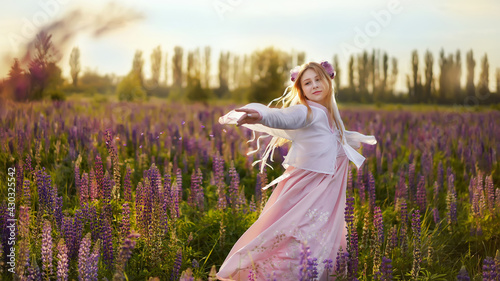 Beautiful blonde girl in a fantasy outfit dress on a field of lupines flowers at sunset in backlight.girl spring hello summer. Magical Photos, Korean Style Clothes.              