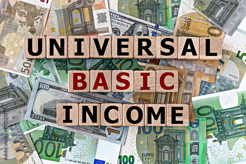 Wallpaper Mural topview photo on universal basic income theme. wooden cubes with the inscription "universal basic income", on the background of dollar and euro bills Torontodigital.ca