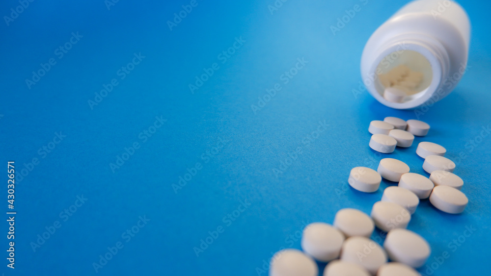 Medicine and healthcare concept. Capsules, tablets scattered near containers on a blue background. Place for your text.