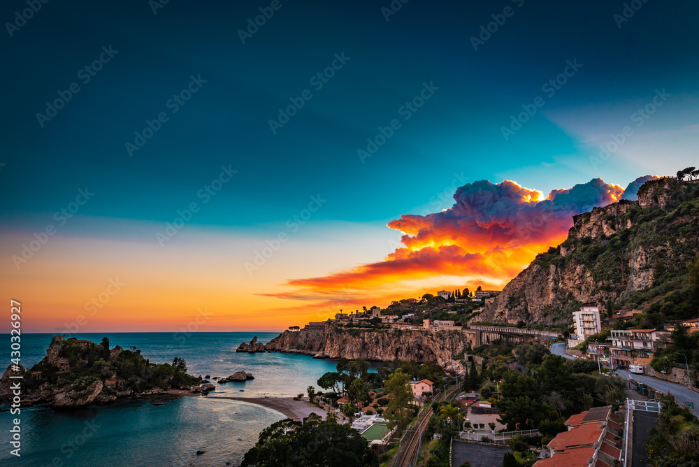 Colorful sunset sky over the bay of Isola Bella- a little island on the Mediterranean coast in Italy 