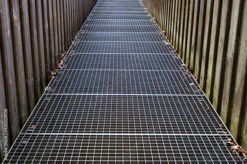 Photography Footbridge with iron grating floor and wooden railing crossing a river