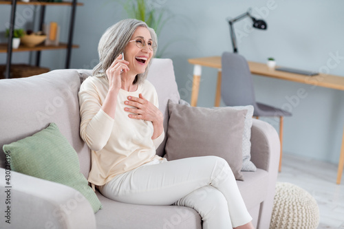 Profile side view portrait of attractive cheerful woman sitting on divan calling friend laughing having fun at home house flat indoor