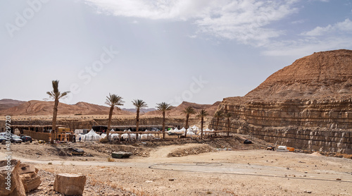 deluxe camping glamping site is under construction in an old gypsum quarry in the Makhtesh Ramon crater in Israel showing new palm trees under a partly cloudy sky