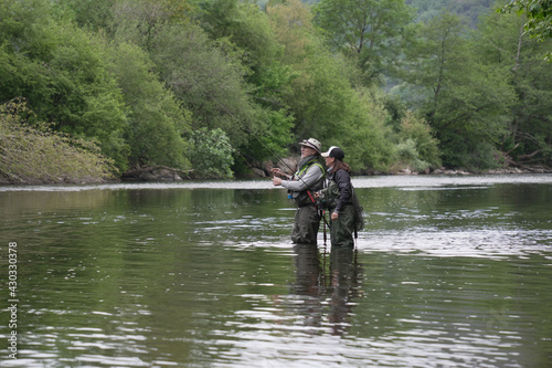 fishing guide with a young woman fly fishing for trout in a clear river