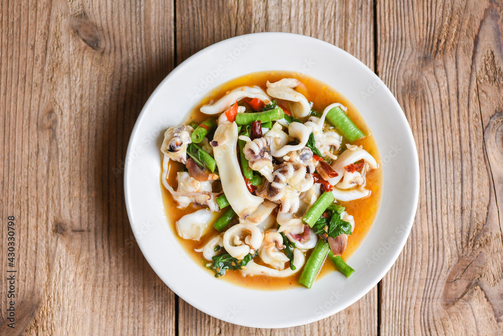 Fried squid with basil on white plate, Stir fried spicy basil leave with squid cuttlefish seafood cooked Thai food Fried squid with basil on white plate, Stir fried spicy basil leave with squid cuttlefish seafood cooked Thai food