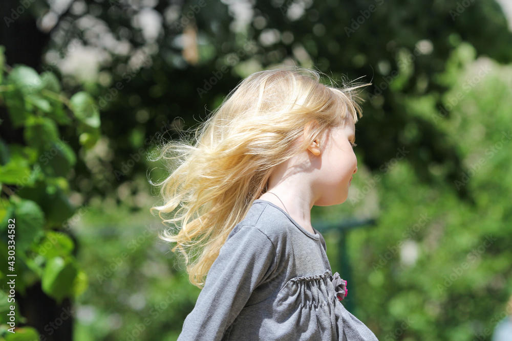Little girl with blonde hair running away on a sunny day. Active children concept. Side view, close up. Little girl with blonde hair running away on a sunny day. Active children concept. Side view, close up.