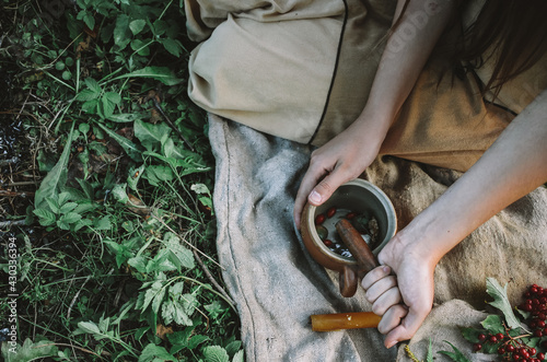 Obraz na plátně Indian shaman preparing healing potion near a fire outdoors, beautiful woman mak