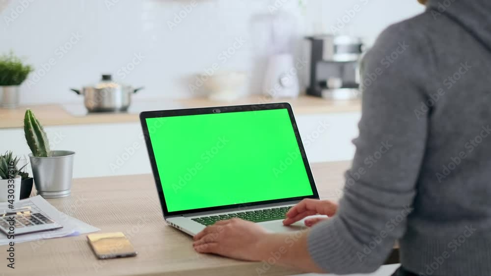 Video of afro business woman using laptop computer with a green screen on monitor in the kitchen at home. Video of afro business woman using laptop computer with a green screen on monitor in the kitchen at home.