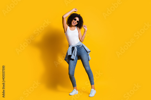 Full length photo of happy afro american lady wear white singlet jacket on waist dance isolated on yellow color background