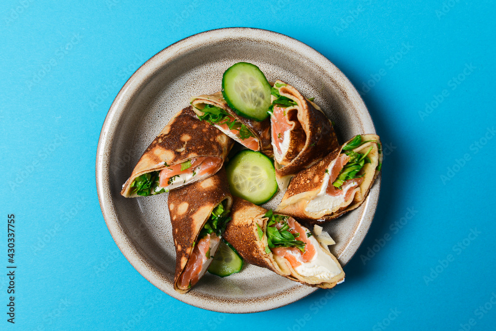 Stack of pancakes with salted salmon and cream cheese Philadelphia in a bowl. Over bright blue background. Stack of pancakes with salted salmon and cream cheese Philadelphia in a bowl. Over bright blue background.