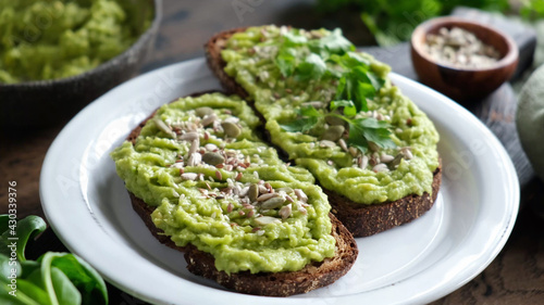 Toast with mashed avocado and seeds on a plate. Healthy vegan vegetarian avocado toasts