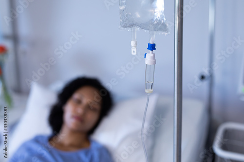 фотографія Mixed race female patient lying asleep in hospital bed hooked up to iv drip, sel
