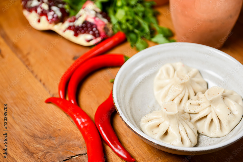 Khinkali cooked on a ceramic plate over rustic wooden background. Khinkali cooked on a ceramic plate over rustic wooden background.