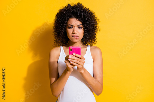 Photo of cute guilty young dark skin lady wear white singlet communicating modern device isolated yellow color background