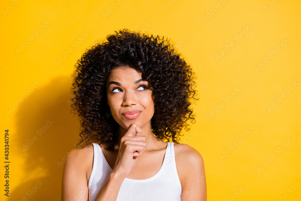 Photo of cute dreamy young dark skin lady wear white singlet looking empty space arm chin isolated yellow color background Photo of cute dreamy young dark skin lady wear white singlet looking empty space arm chin isolated yellow color background