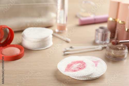 Dirty cotton pads, swabs and cosmetic products on wooden table