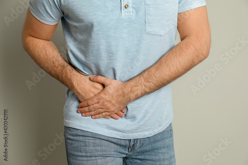 Man suffering from acute appendicitis on light grey background, closeup