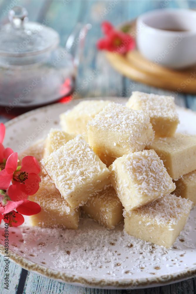 Apple gelatin dessert. Sugar free pastila. Homemade apple marshmallow cubes in coconut flakes and tea, blooming japanese quince decoration Apple gelatin dessert. Sugar free pastila. Homemade apple marshmallow cubes in coconut flakes and tea, blooming japanese quince decoration