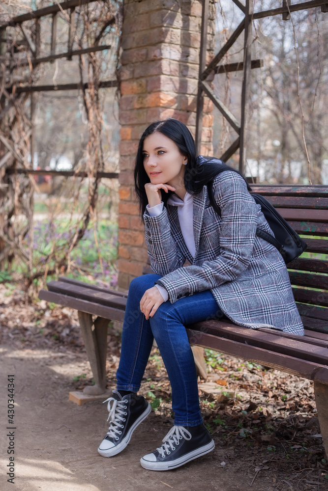 Portrait of young brunette woman in plaid coat in park enjoying the nature Portrait of young brunette woman in plaid coat in park enjoying the nature