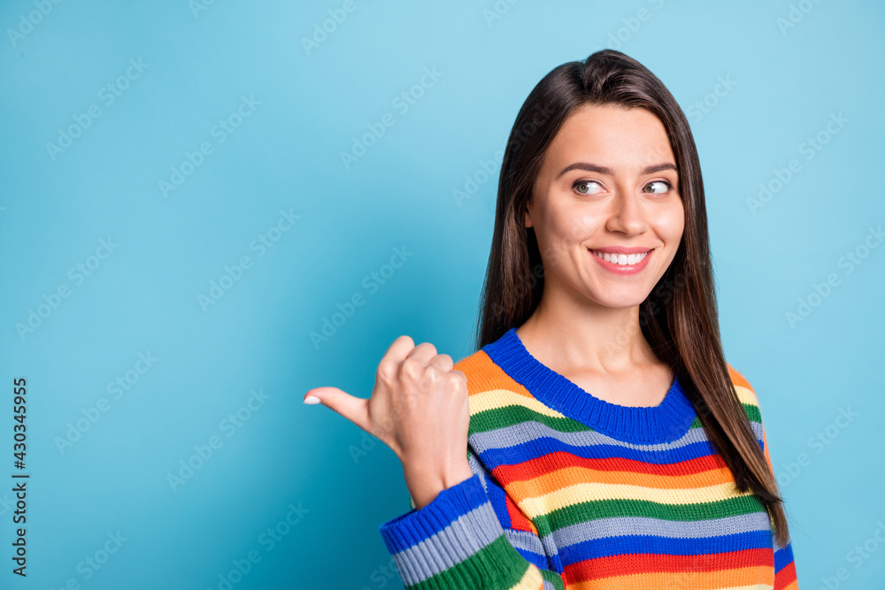 Photo portrait of girl curious pointing thumb blank space advertising smiling isolated on vibrant blue color background Photo portrait of girl curious pointing thumb blank space advertising smiling isolated on vibrant blue color background