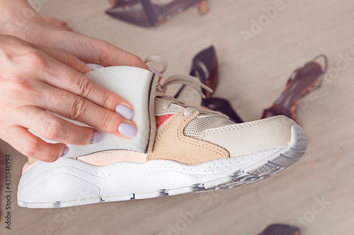 Cleaning sport shoes. Female hands holding  melamine spong and sport sneakers