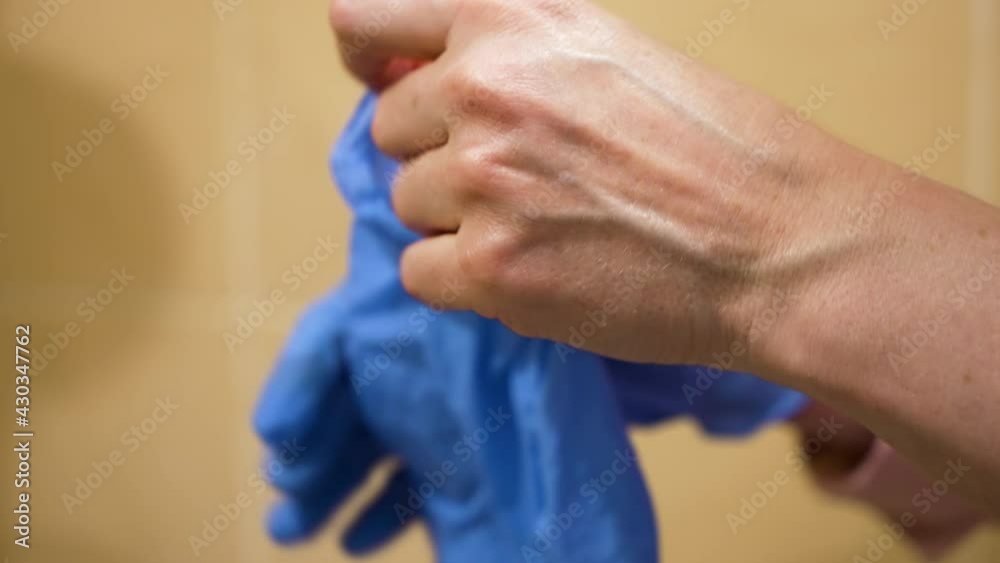 Female hands putting on blue latex gloves, blurred background. Closeup nurse preparing for visiting patient in hospital. Protective measures during pandemic. Concept of healthcare Female hands putting on blue latex gloves, blurred background. Closeup nurse preparing for visiting patient in hospital. Protective measures during pandemic. Concept of healthcare