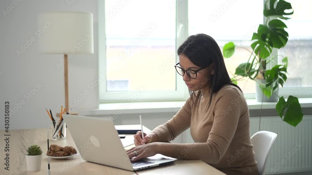 Beautiful African woman writes data from computer in notebook at table Spbd. Beautiful African woman writes data from computer in notebook at table Spbd.