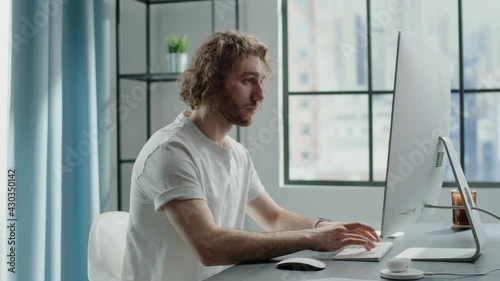 Blond freelancer works on computer and chats on smartphone photo