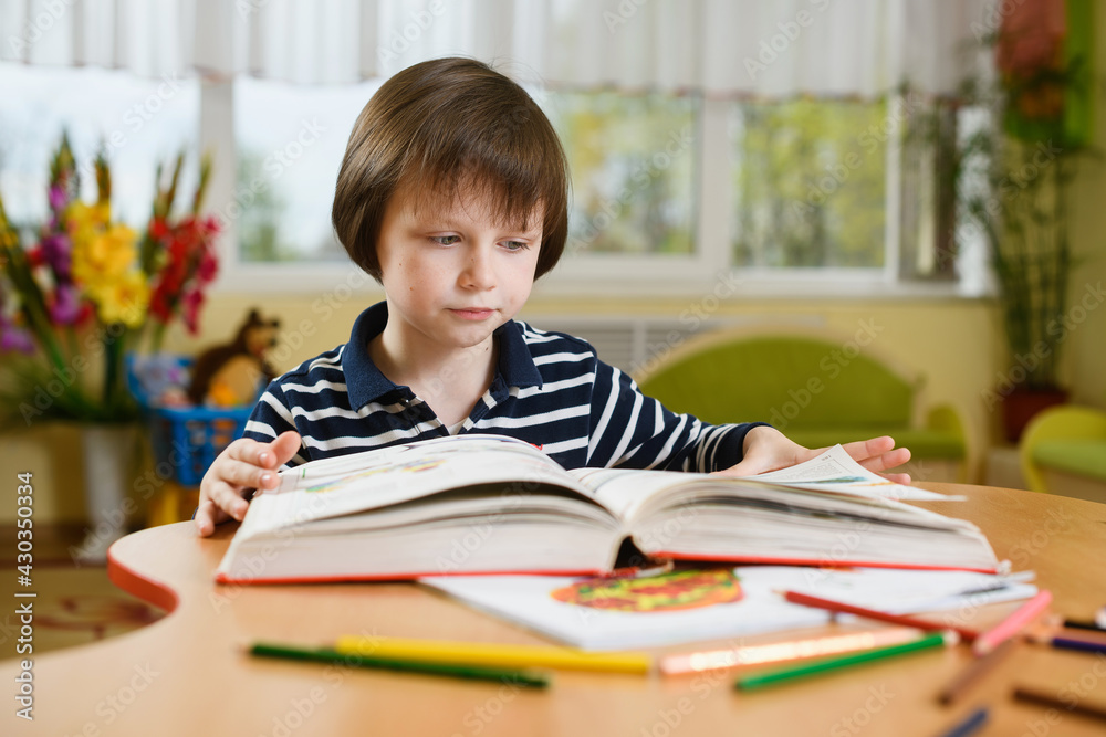 A preschool boy is reading a huge book. A preschool boy is reading a huge book.