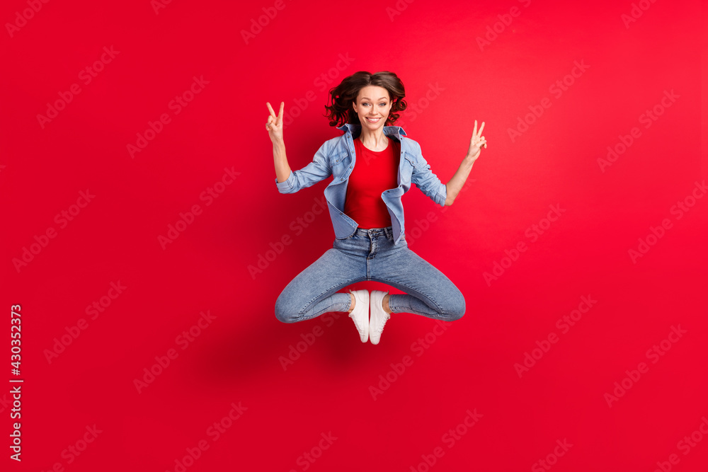 Full length body size photo of cheerful girl jumping up yoga pose showing v-sign gesture isolated vivid red color background Full length body size photo of cheerful girl jumping up yoga pose showing v-sign gesture isolated vivid red color background