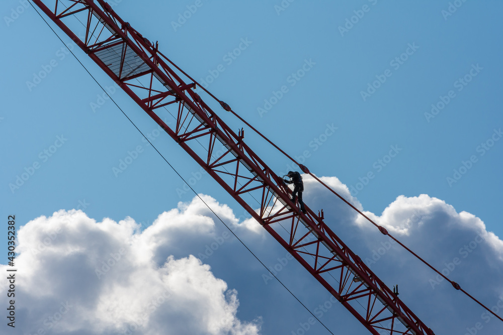 High-rise worker on a crane boom against the background of clouds High-rise worker on a crane boom against the background of clouds