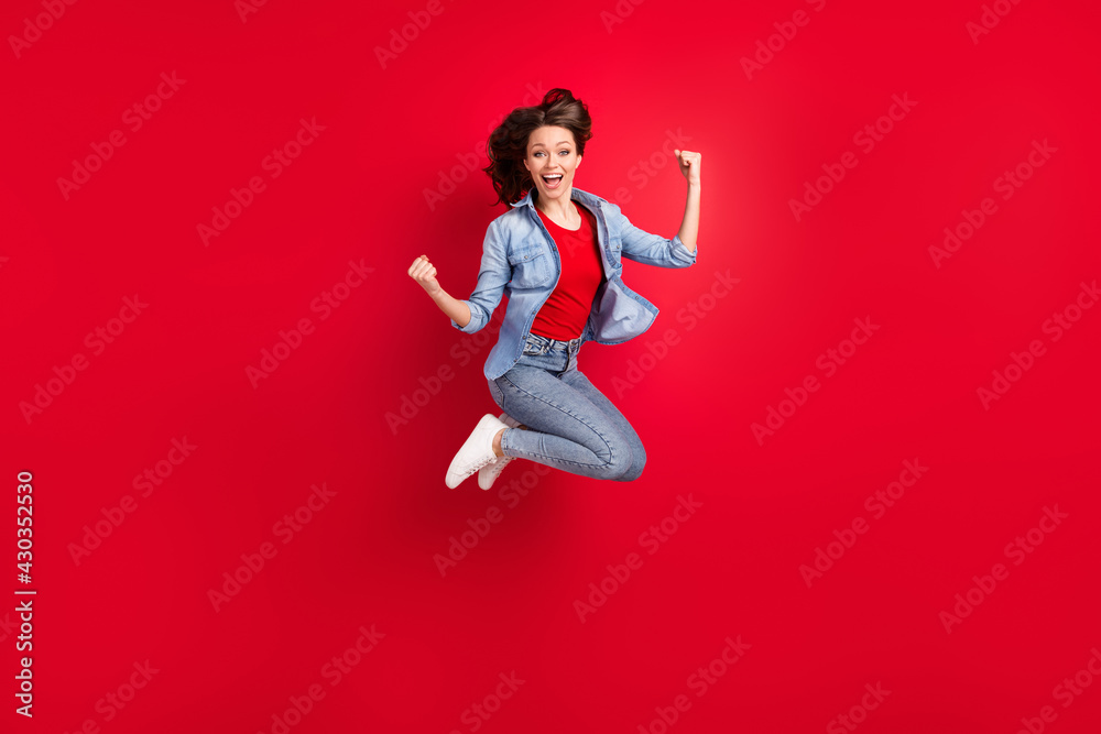 Full length body size photo of girl jumping up gesturing like winner isolated on vibrant red color background with copyspace