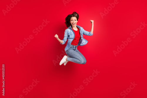 Full length body size photo of girl jumping up gesturing like winner isolated on vibrant red color background with copyspace