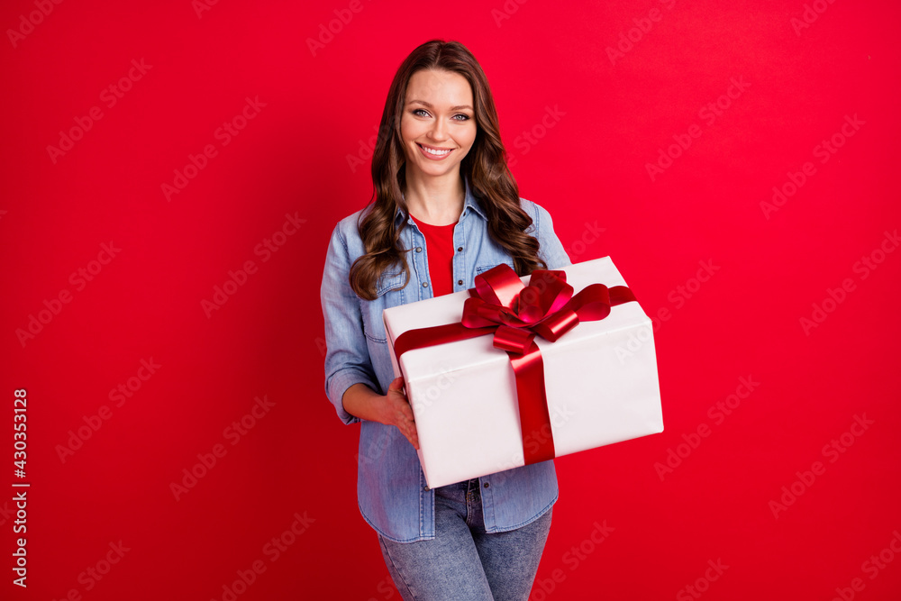 Portrait of attractive cheerful girl holding in hands festal giftbox party isolated over vibrant red color background Portrait of attractive cheerful girl holding in hands festal giftbox party isolated over vibrant red color background