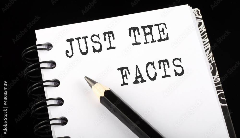 JUST THE FACTS written text in small notebook on a black background JUST THE FACTS written text in small notebook on a black background