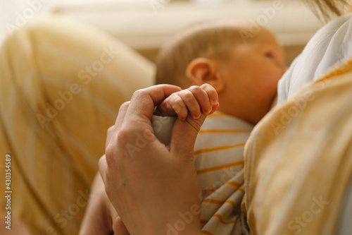 Newborn baby boy sucking milk from mothers breast. Portrait of mom and breastfeeding baby.