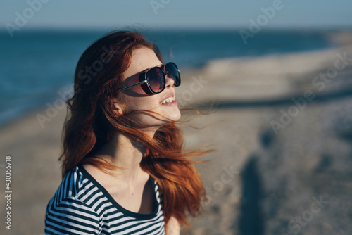 woman in glasses and in a striped T-shirt at sunset or there near the sea view from the balcony