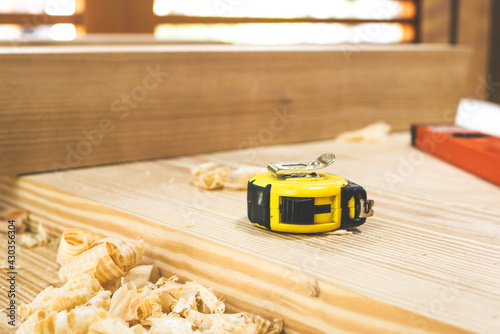 Tape measure on a wooden desk in carpentry shop.